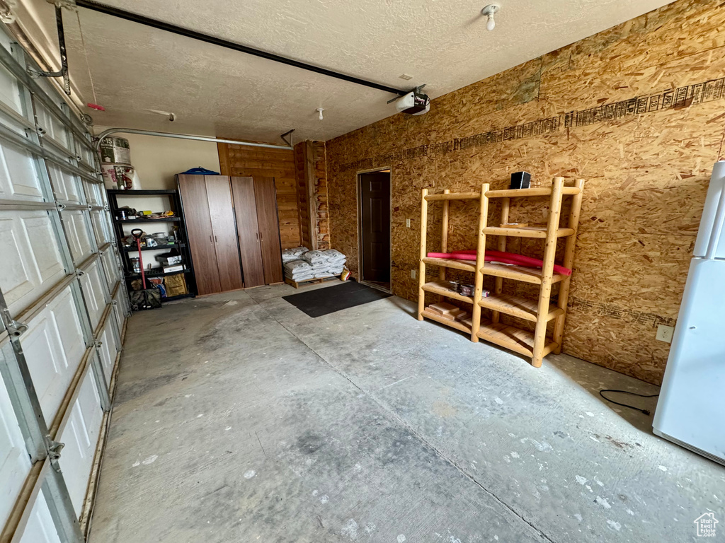 Garage with a garage door opener and freestanding refrigerator
