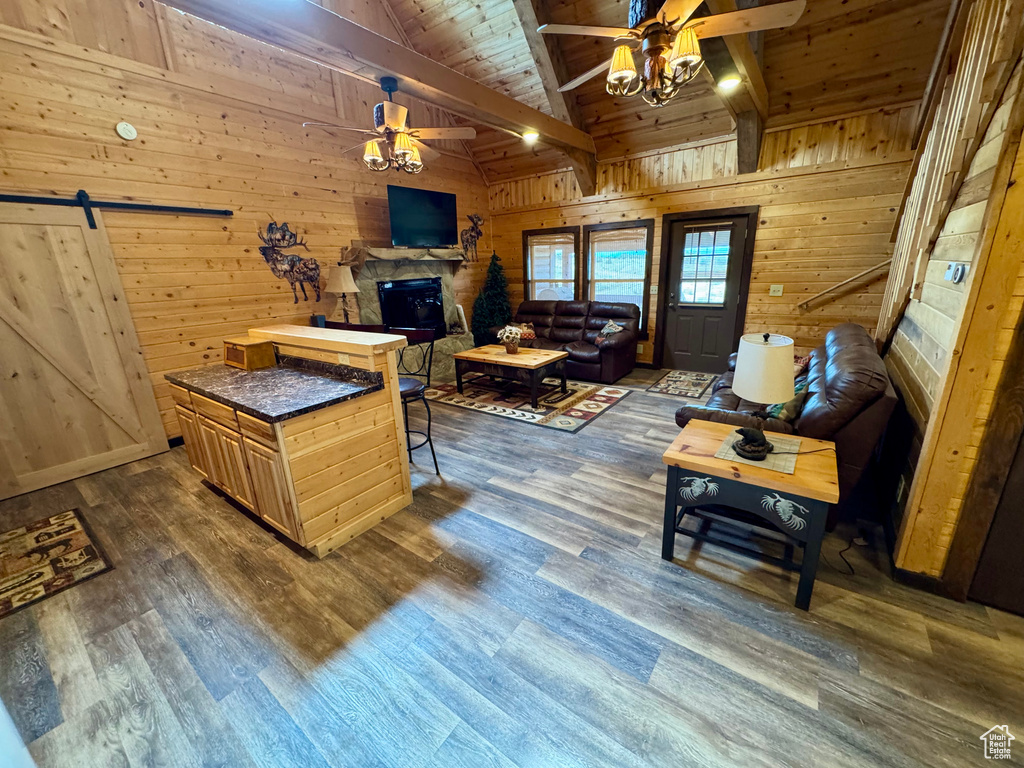 Living area featuring a ceiling fan, wooden walls, beam ceiling, wooden ceiling, and a barn door