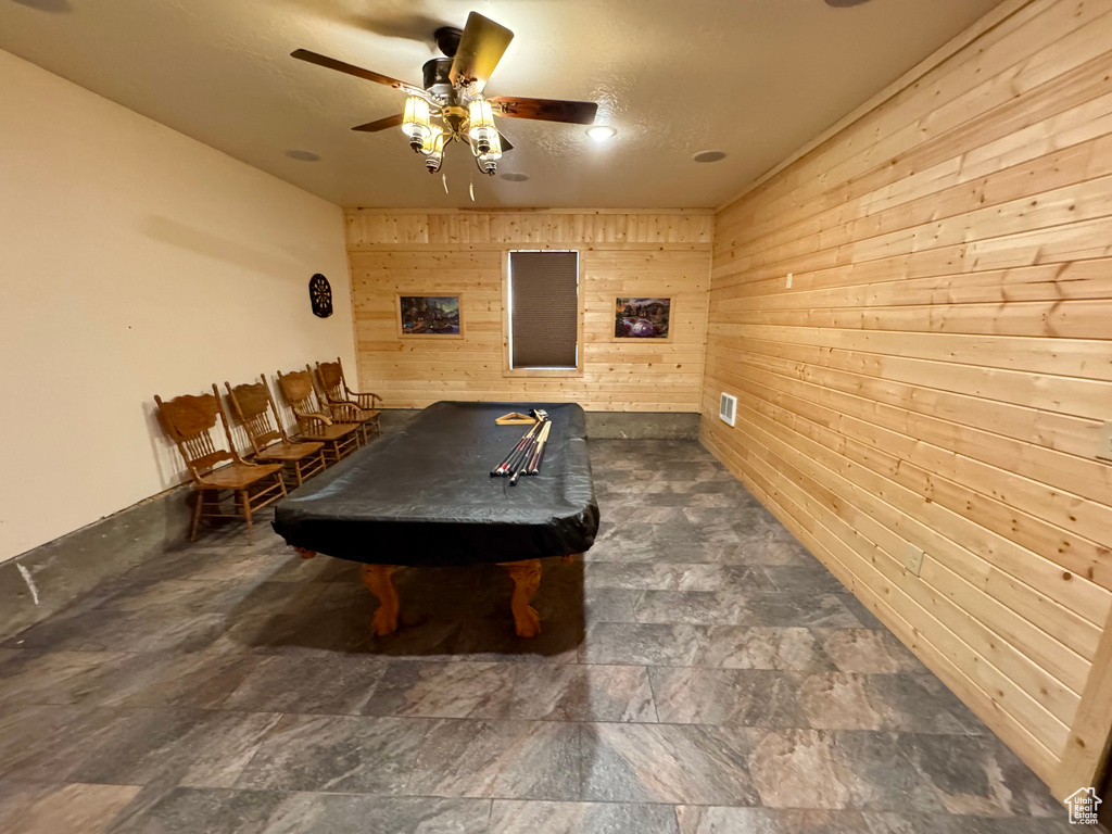 Game room featuring wooden walls, billiards table, a ceiling fan, and dark stone finish flooring