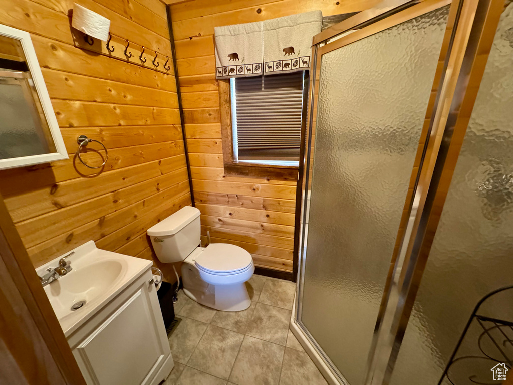 Bathroom with wood walls, a stall shower, vanity, tile patterned flooring, and toilet