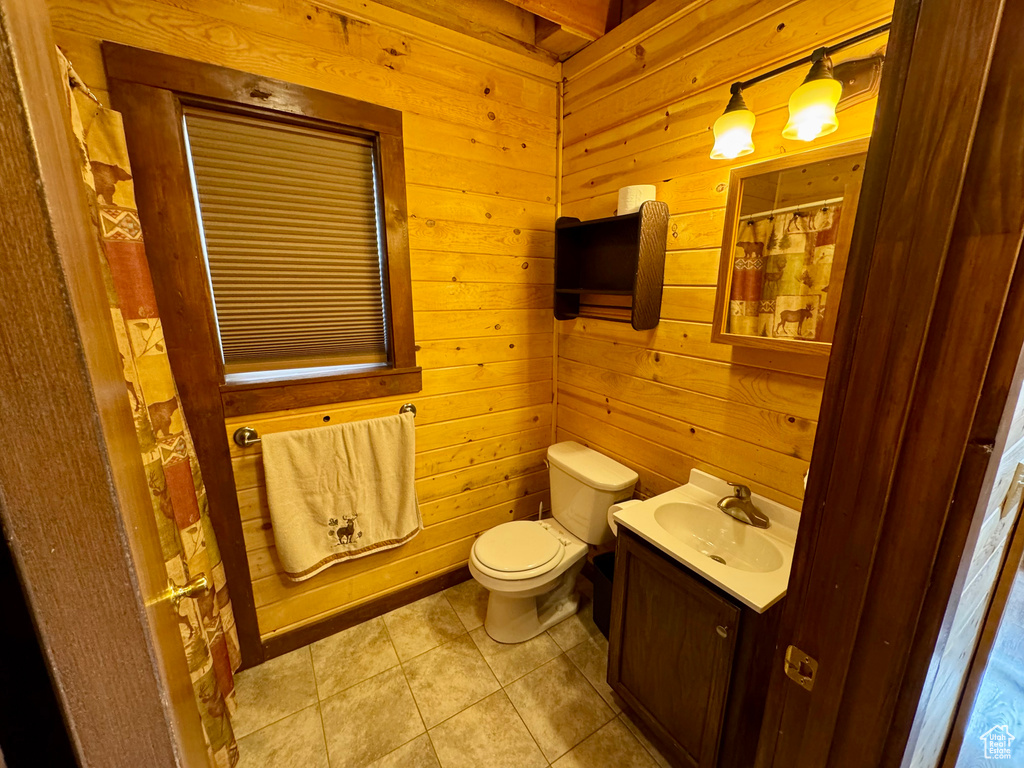 Bathroom with wood walls, tile patterned floors, toilet, vanity, and a shower with curtain
