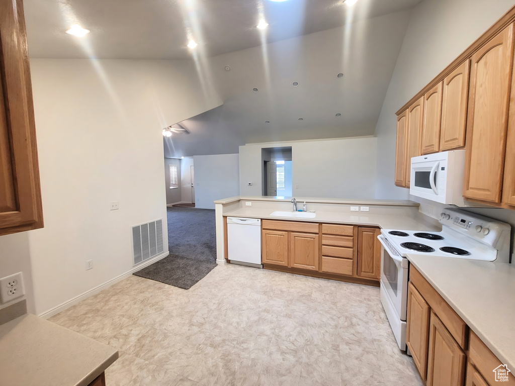 Kitchen with white appliances, a sink, vaulted ceiling, a peninsula, and open floor plan