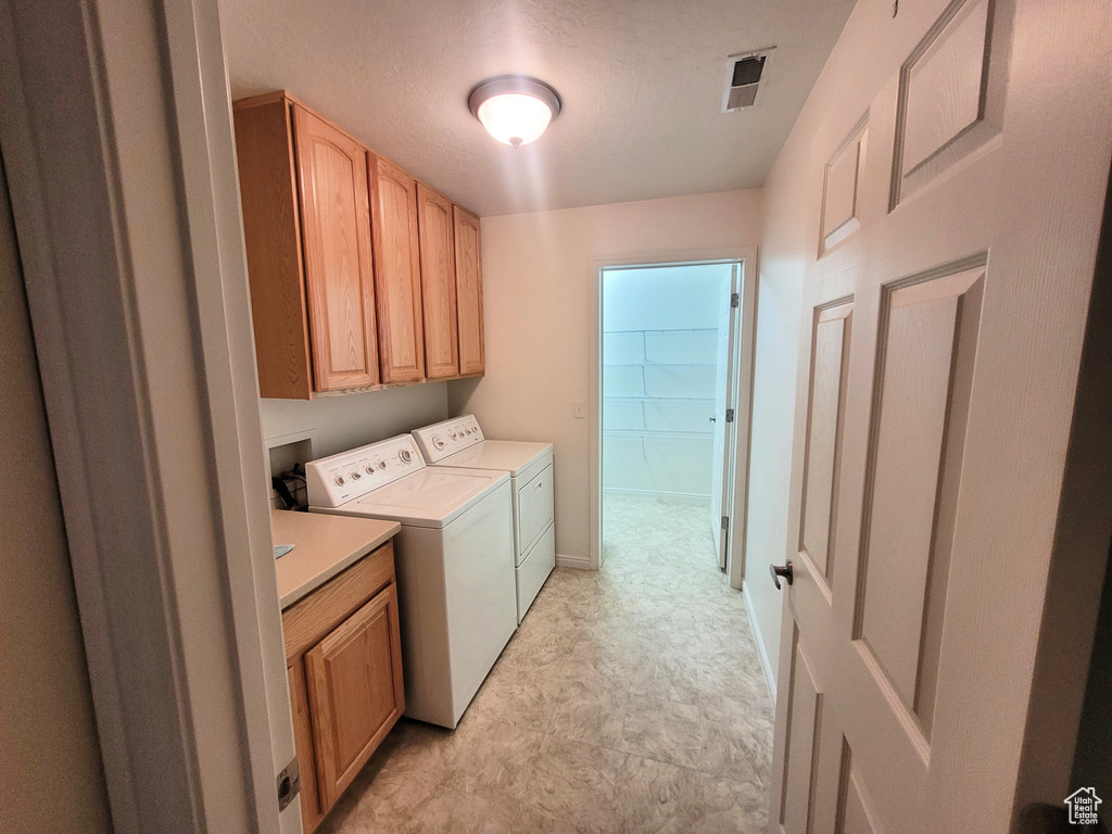 Laundry room featuring cabinet space, washing machine and dryer, light flooring, and baseboards