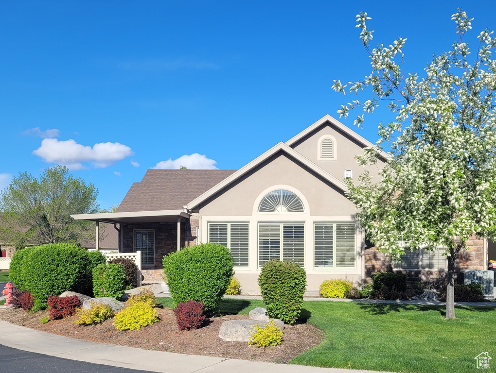 View of front of house with stucco siding, stone siding, and a front lawn