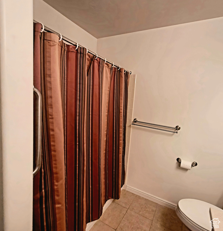 Bathroom featuring toilet, tile patterned flooring, and baseboards