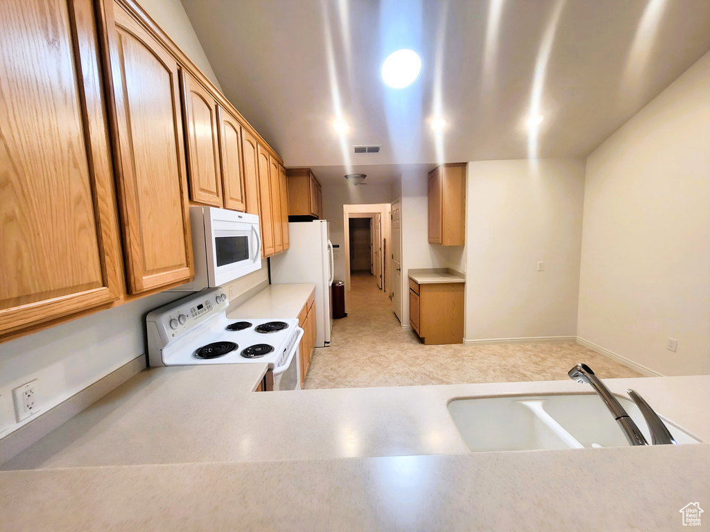 Kitchen featuring white appliances, light countertops, and a sink