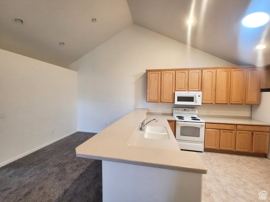 Kitchen with white appliances, a peninsula, a sink, light countertops, and vaulted ceiling