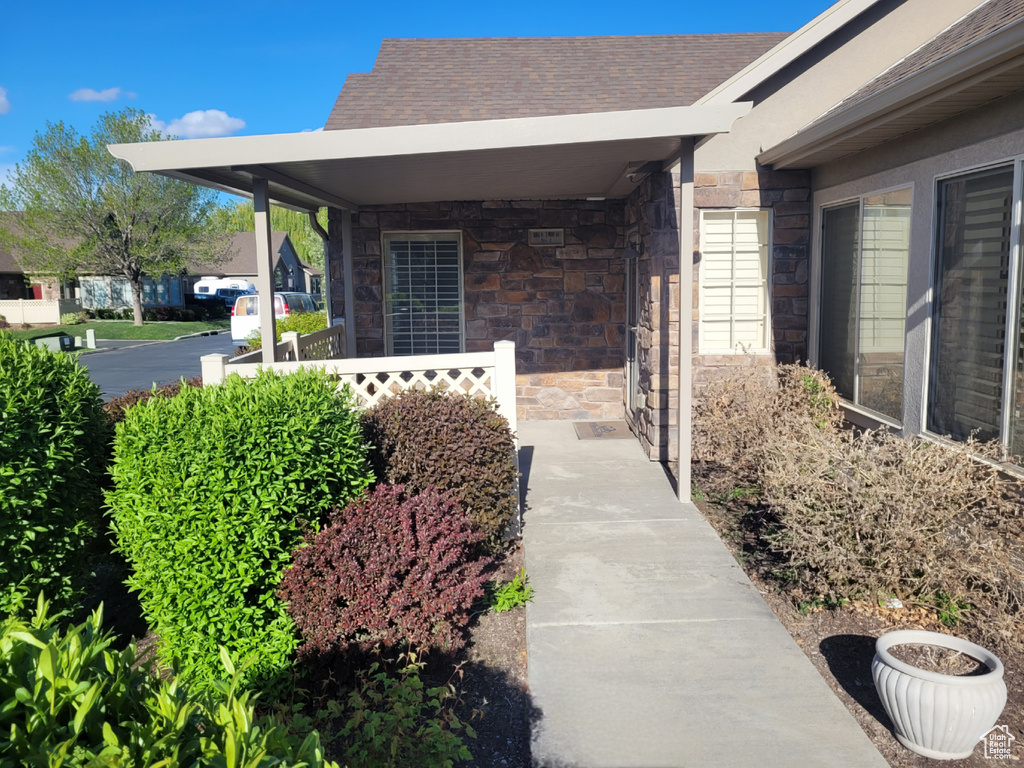 Exterior space featuring covered porch, a shingled roof, and stone siding