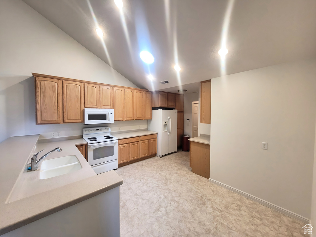 Kitchen featuring white appliances, a sink, light countertops, light flooring, and vaulted ceiling