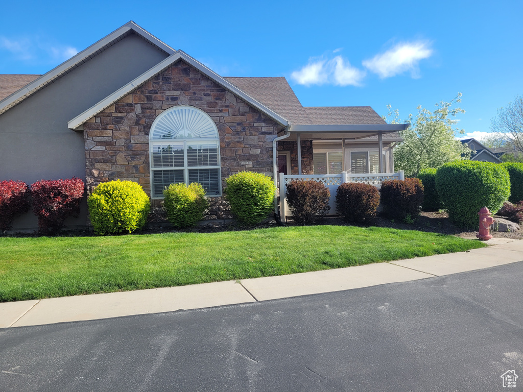 Ranch-style home with a porch, stone siding, and a front lawn