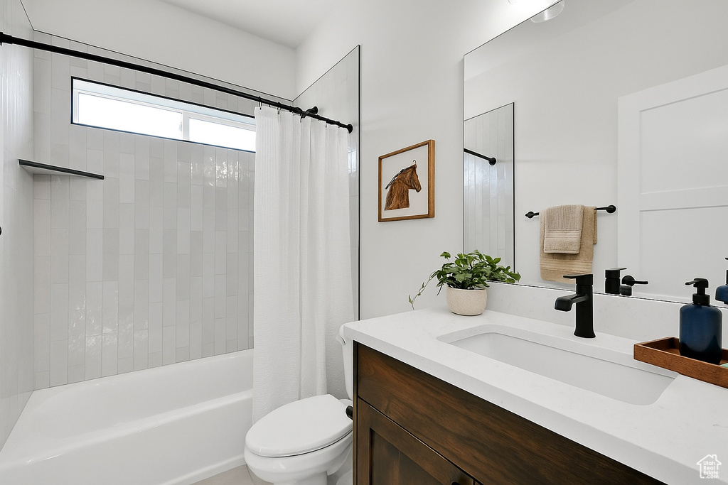 Bathroom with vanity, toilet, and shower / tub combo with curtain