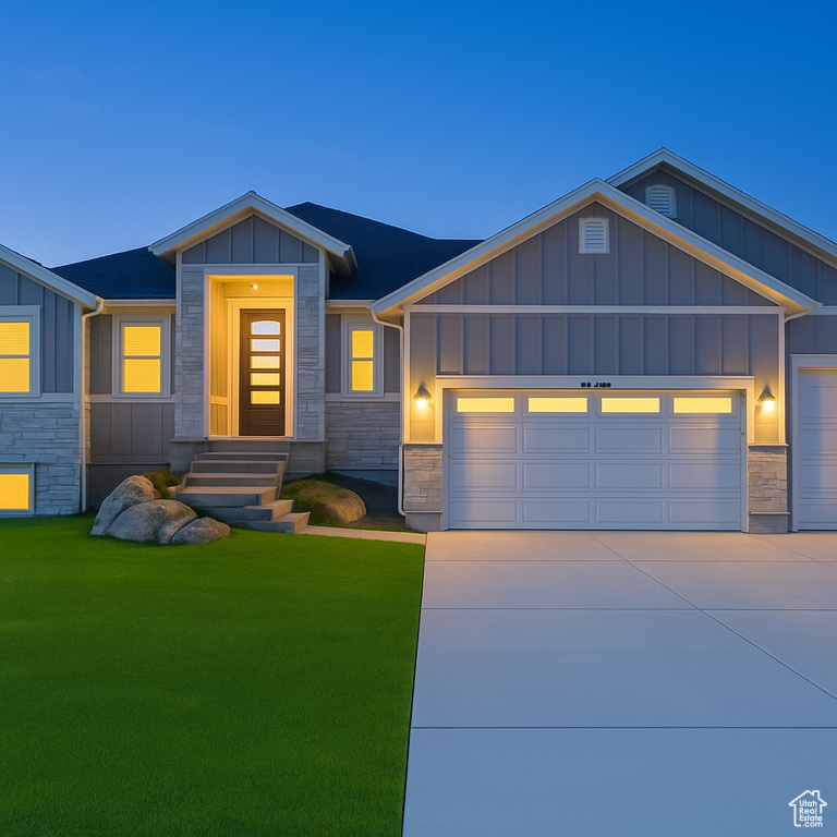 View of front facade with board and batten siding, stone siding, and a garage