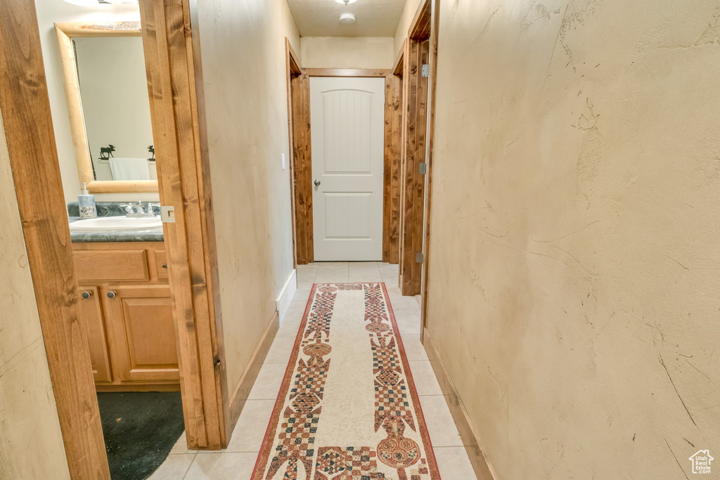 Hall featuring a sink, baseboards, inlaid floor details, and light tile patterned floors