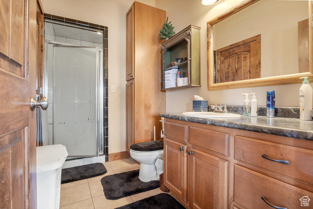 Bathroom featuring toilet, tile patterned floors, a stall shower, and vanity