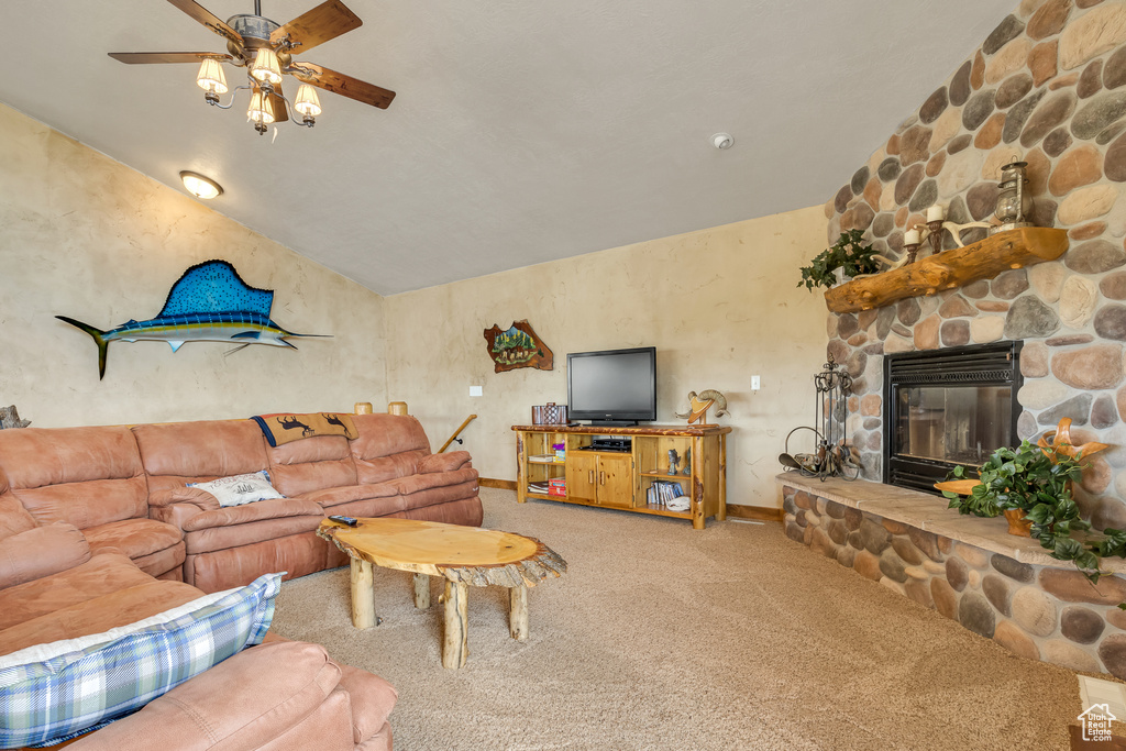Carpeted living room featuring a ceiling fan, vaulted ceiling, a fireplace, and baseboards