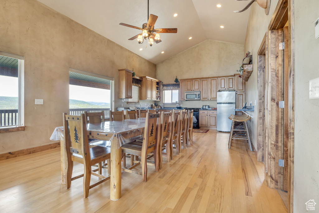 Dining space with a ceiling fan, light wood-style flooring, high vaulted ceiling, and recessed lighting