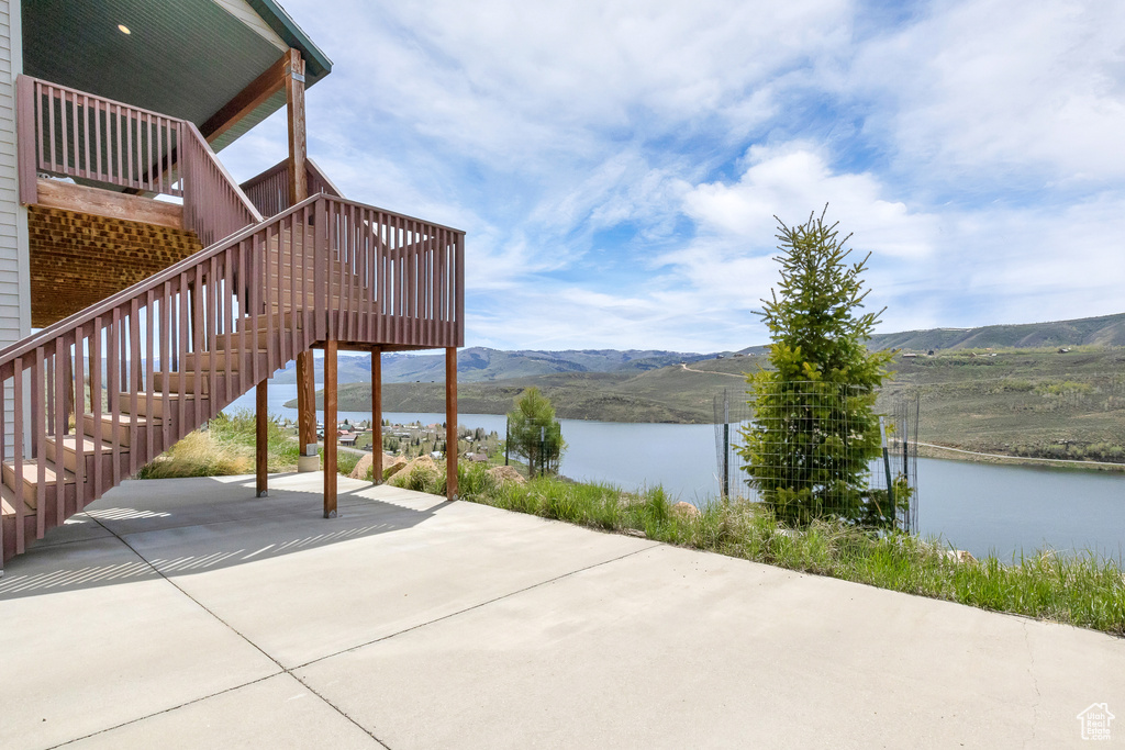 View of patio with a water and mountain view and stairway