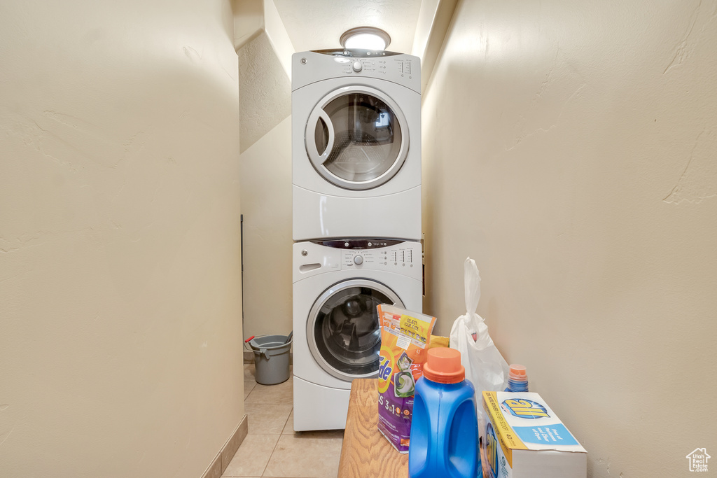 Laundry room featuring stacked washer / drying machine and light tile patterned flooring