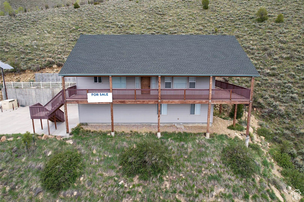 Back of house featuring a patio, roof with shingles, a deck, stairway, and fence