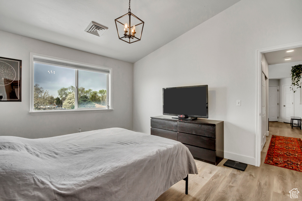 Bedroom with a chandelier, light wood-style floors, vaulted ceiling, and baseboards