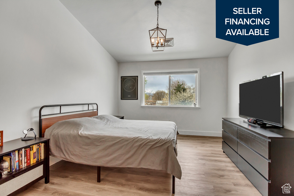 Bedroom with a chandelier, light wood-type flooring, and baseboards