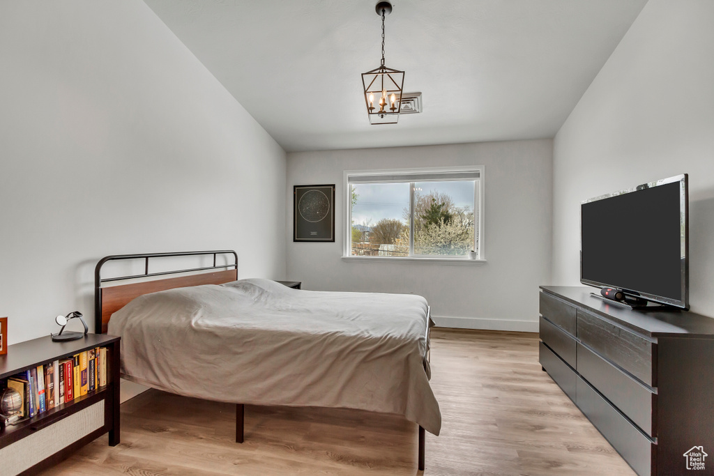 Bedroom with a chandelier, light wood finished floors, and baseboards