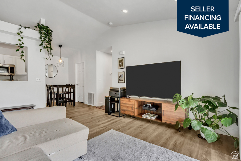Living room with wood finished floors, vaulted ceiling, recessed lighting, and baseboards