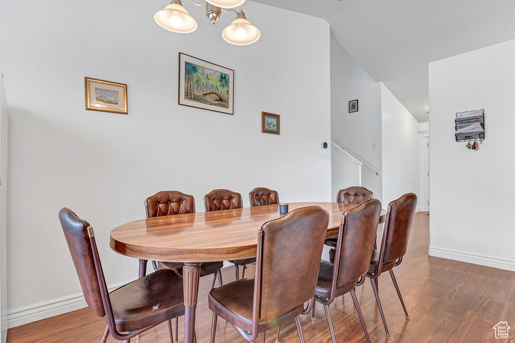 Dining room featuring wood finished floors, baseboards, stairs, and lofted ceiling