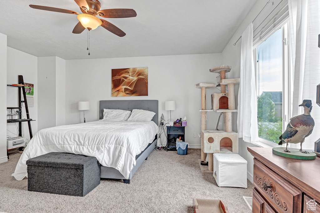Bedroom with light colored carpet, baseboards, and ceiling fan