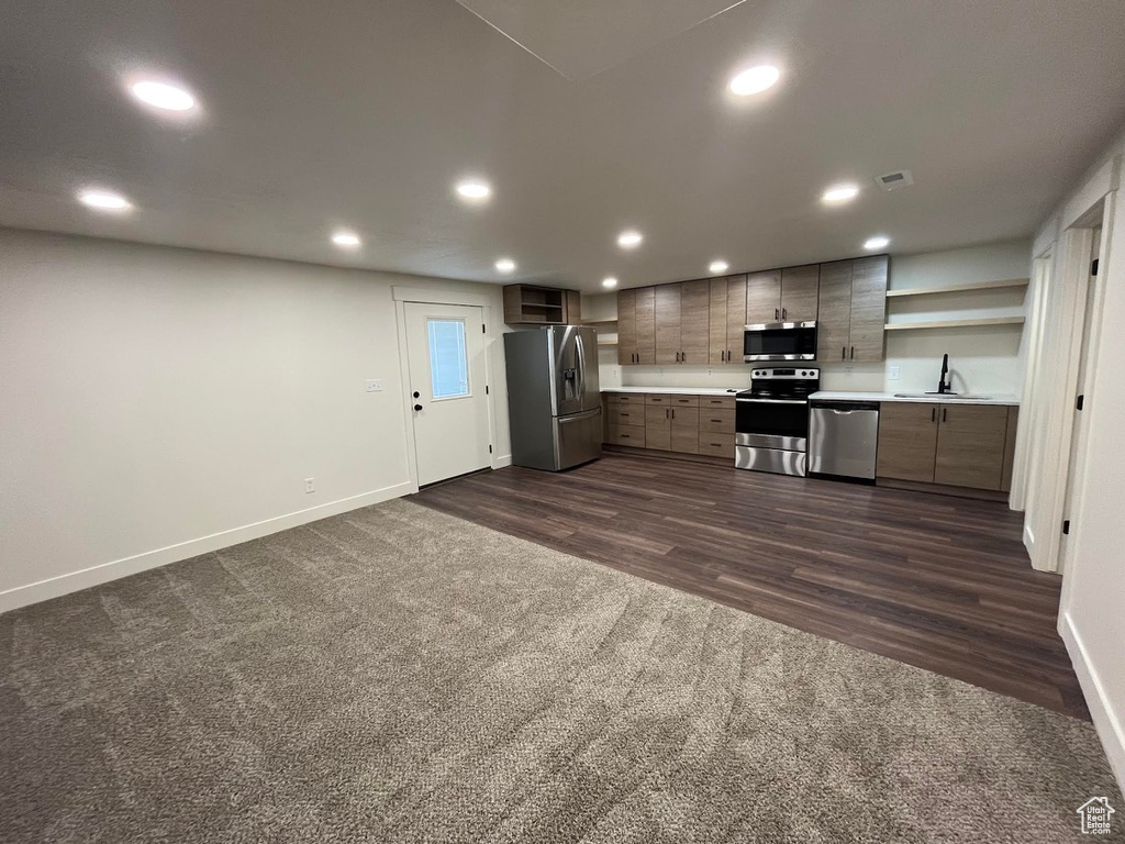 Kitchen featuring stainless steel appliances, baseboards, dark colored carpet, open shelves, and light countertops
