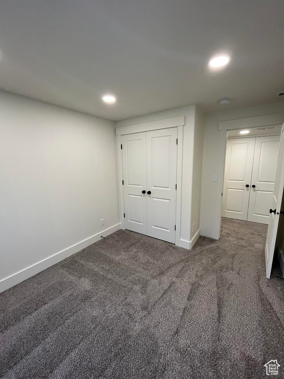 Unfurnished bedroom with recessed lighting, baseboards, dark carpet, and a closet
