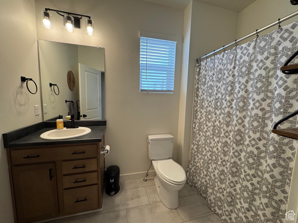 Bathroom featuring tile patterned floors, vanity, toilet, baseboards, and curtained shower