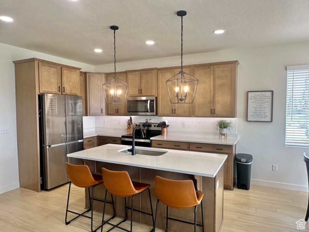 Kitchen with appliances with stainless steel finishes, a sink, baseboards, tasteful backsplash, and recessed lighting
