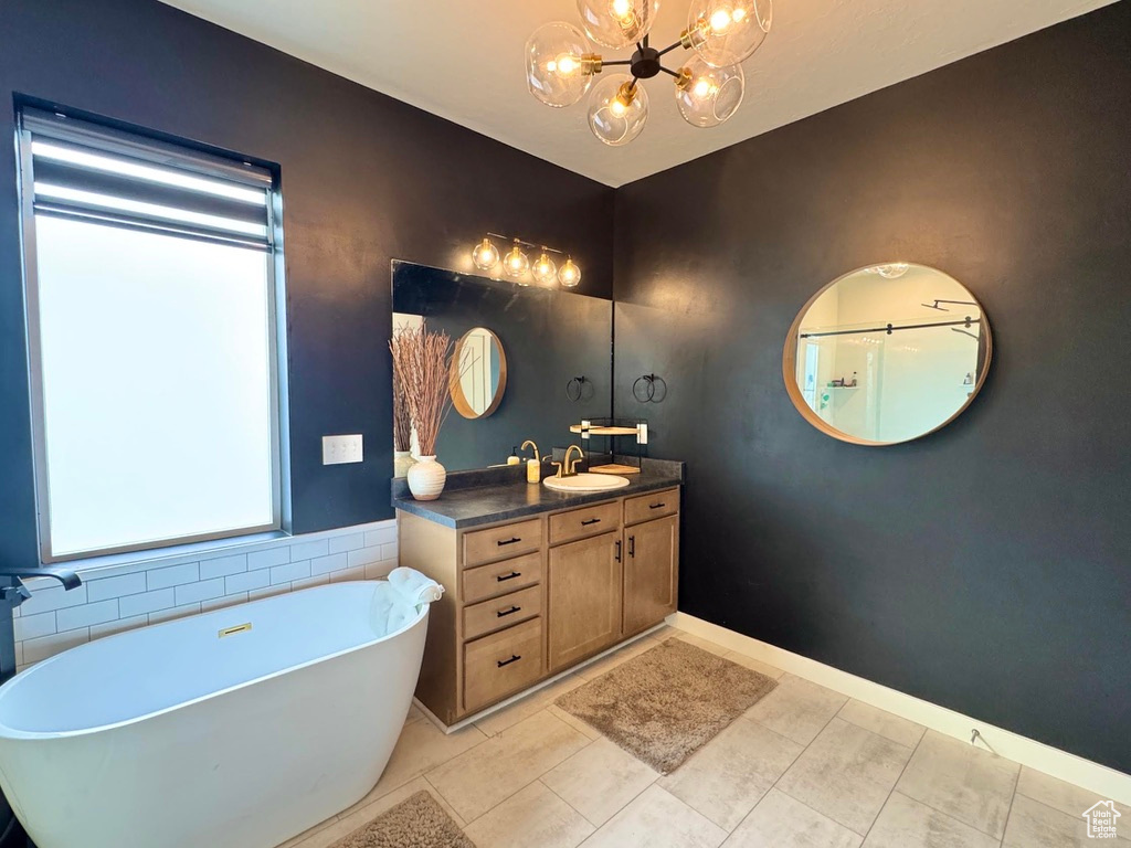Full bath with a chandelier, a freestanding bath, tile patterned floors, and vanity