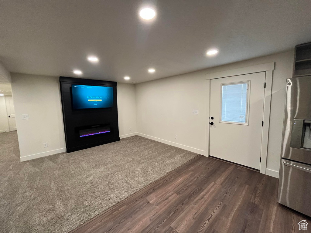 Unfurnished living room featuring dark wood finished floors, recessed lighting, baseboards, and a fireplace