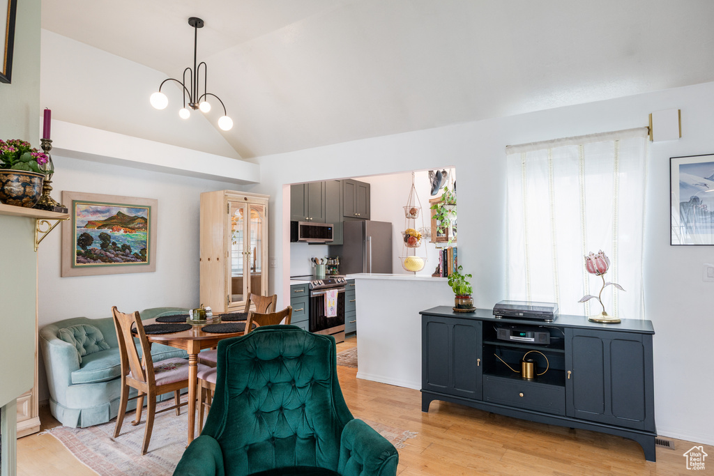 Dining room featuring vaulted ceiling, light wood-style flooring, and a chandelier