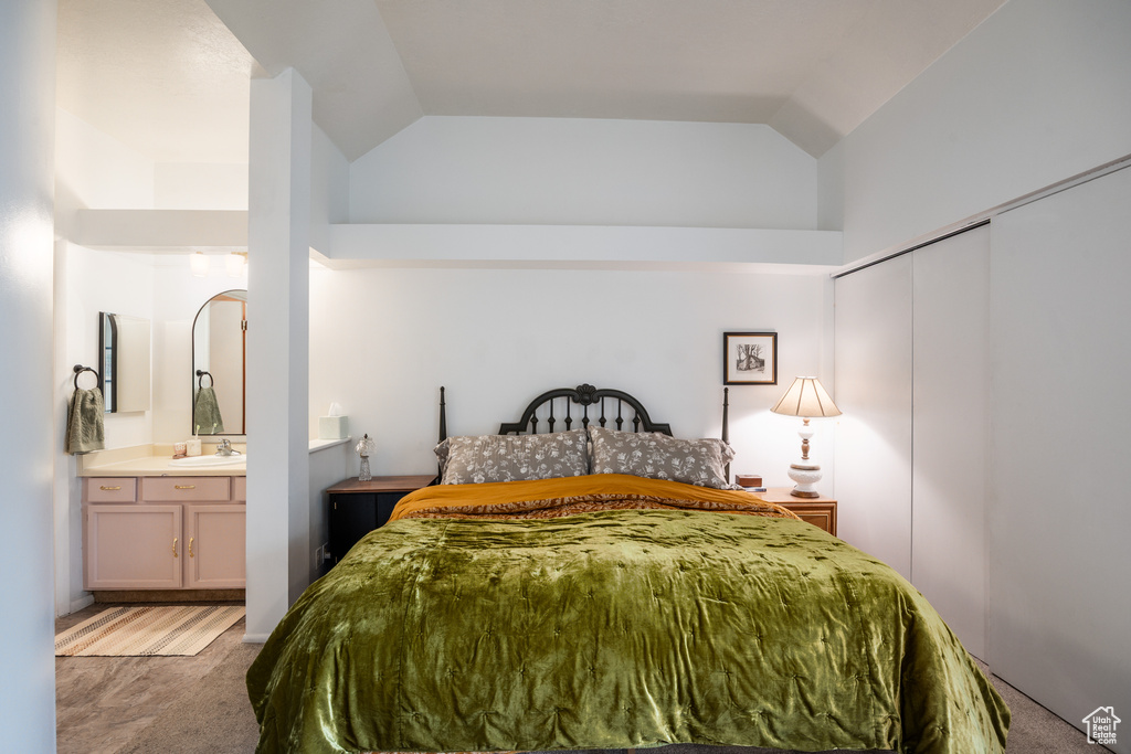 Bedroom with light carpet, high vaulted ceiling, a sink, connected bathroom, and a closet