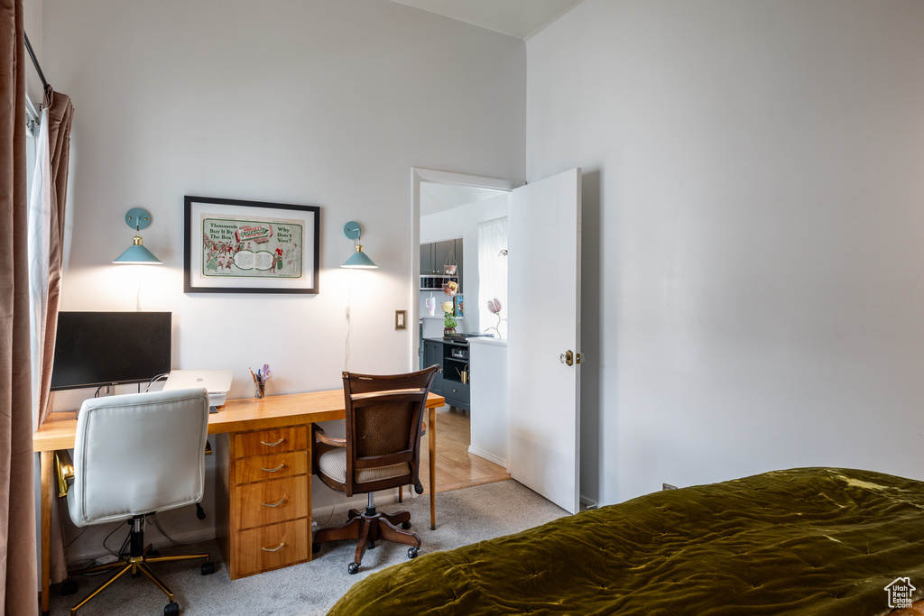 Bedroom with light colored carpet and an office area