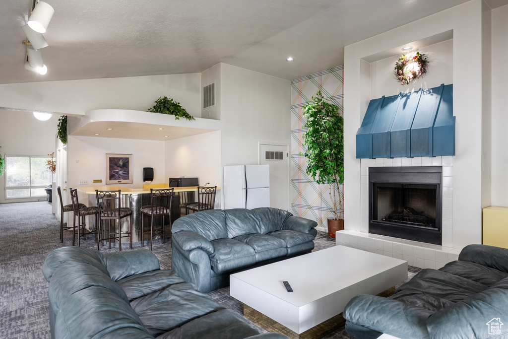Carpeted living area with a tile fireplace and high vaulted ceiling