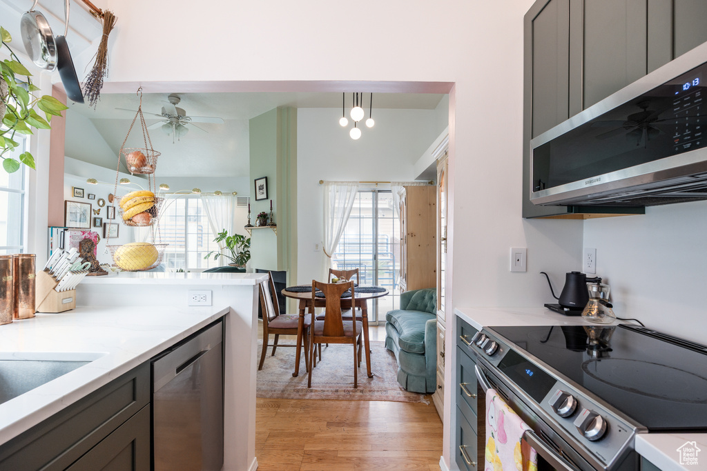 Kitchen featuring stainless steel appliances, light wood-type flooring, plenty of natural light, a ceiling fan, and vaulted ceiling