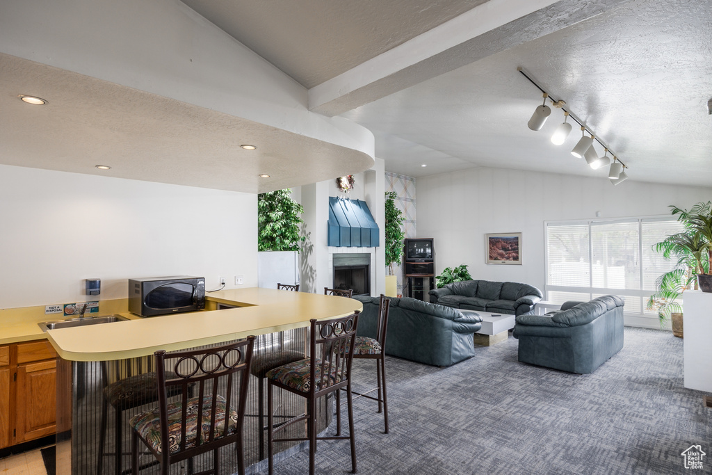 Dining space with vaulted ceiling, a fireplace, recessed lighting, track lighting, and a textured ceiling