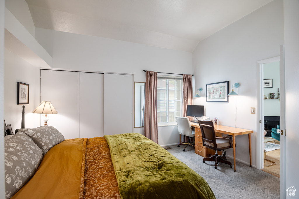 Bedroom with carpet, lofted ceiling, a desk, a closet, and baseboards
