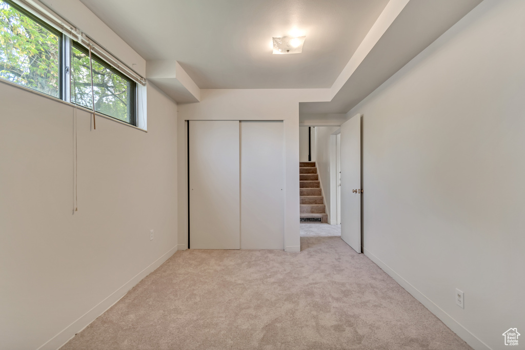Unfurnished bedroom featuring light colored carpet, a closet, and baseboards