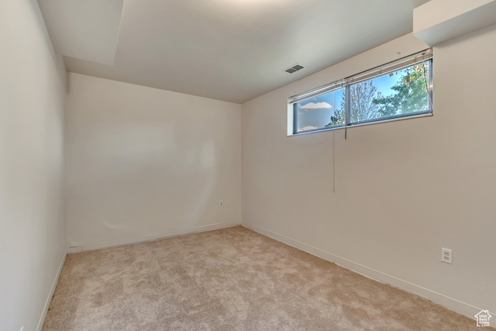 Empty room with light colored carpet and baseboards