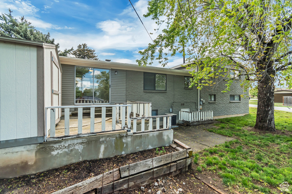 Rear view of property featuring cooling unit and a deck