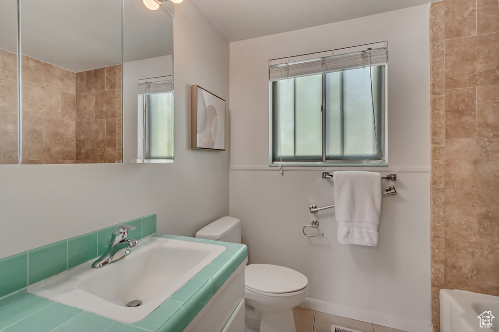 Bathroom with plenty of natural light, toilet, a bath, and tile patterned flooring