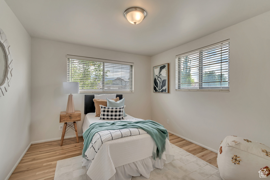 Bedroom with multiple windows, light wood-style floors, and baseboards