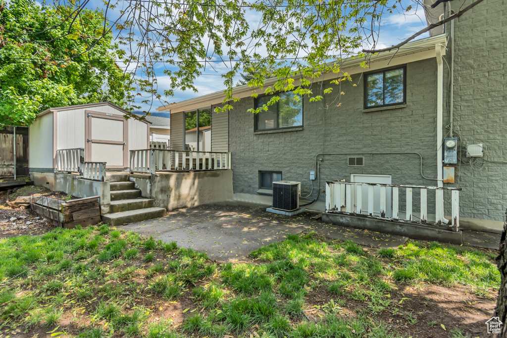 Back of property featuring a shed, a patio area, an outbuilding, and cooling unit