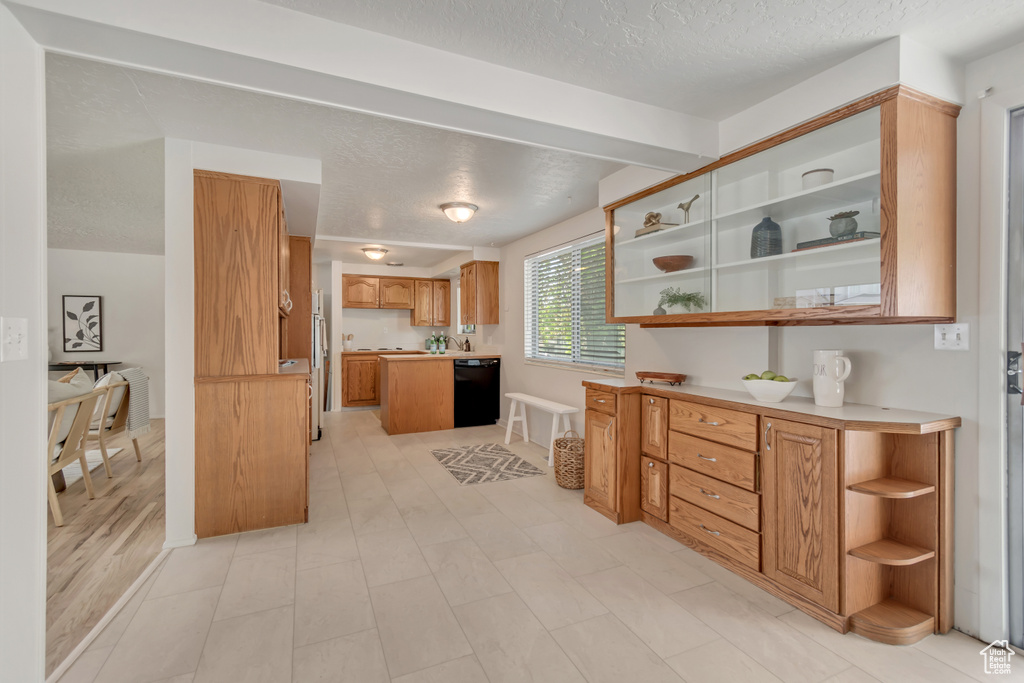 Kitchen with dishwasher, open shelves, a textured ceiling, light countertops, and brown cabinetry