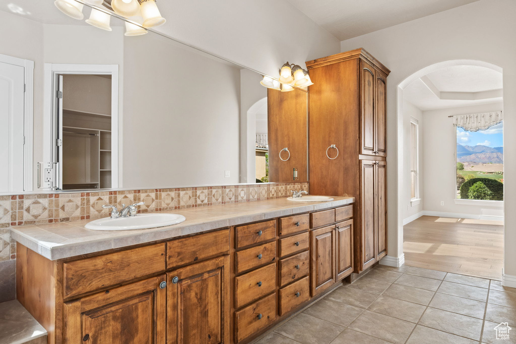 Full bath featuring tasteful backsplash, tile patterned flooring, and double vanity